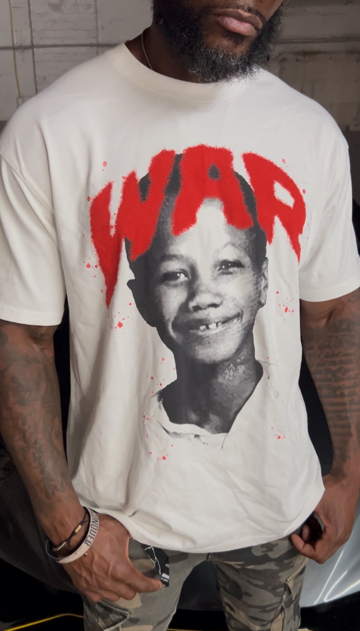 Person with positive energy wearing a white t-shirt with a graphic design of a child's face and the word 'WAR' in red.